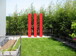 Kunstwerk im Garten: Drei rote Säulen als Blickfang